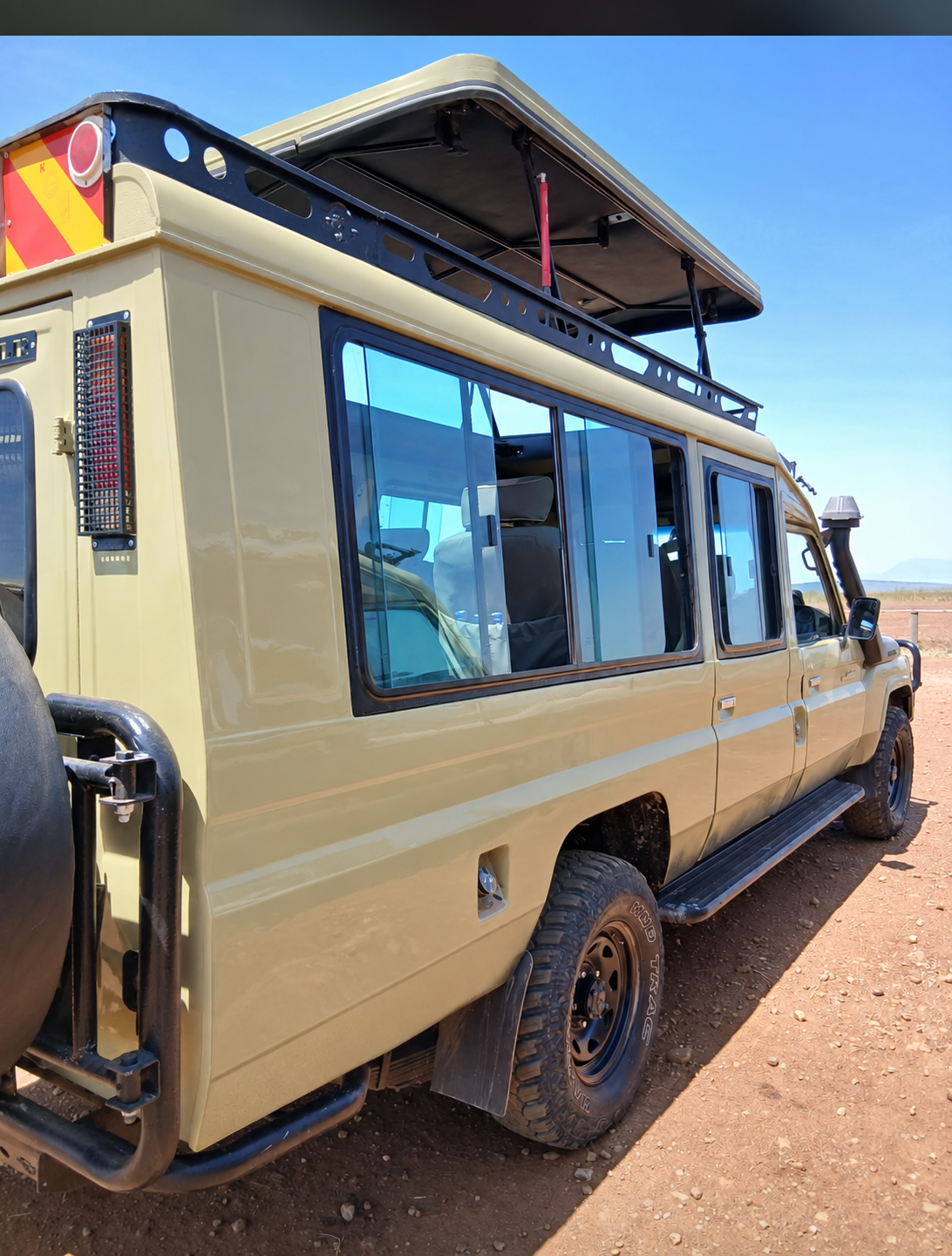 Enclosed safari Toyota Land Cruiser with large windows and a raised viewing roof